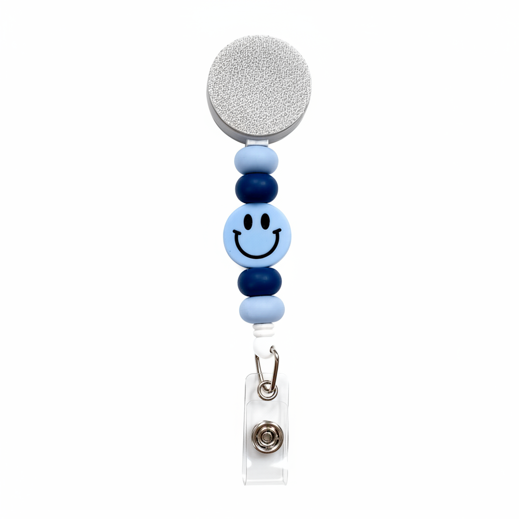 Blue Smiley Face badge reel featuring a light blue happy face design with light blue and navy blue decorative beads, retractable badge reel functionality, and secure badge holder attachment.