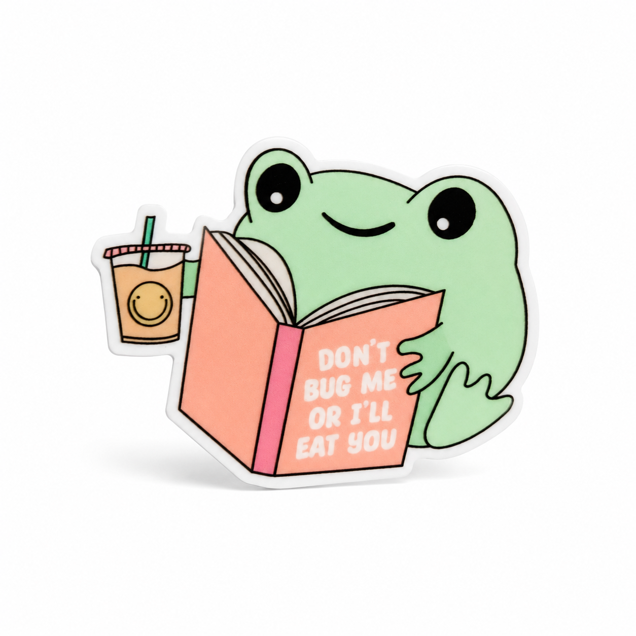 DON’T BUG ME OR I’LL EAT YOU plastic add-on with a green frog reading a coral book beside a drink, compatible with interchangeable badge reel bases.