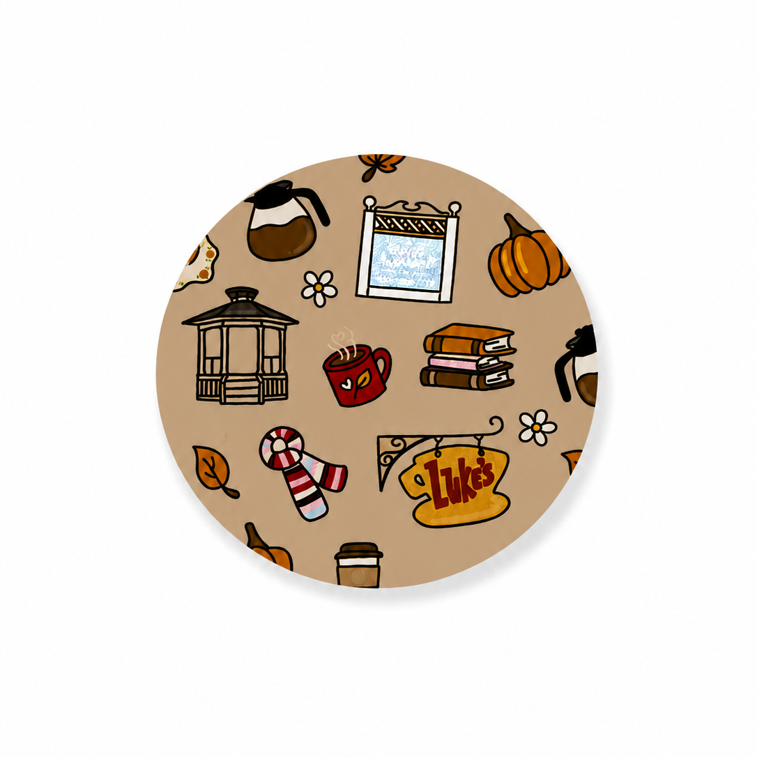 Fall in Stars Hollow hard board add-on featuring a gazebo, coffee mugs, coffee pot, books, pumpkins, autumn leaves, flowers, window scene, and Luke's café sign. Compatible with interchangeable badge reel bases and ideal as a cozy work badge accessory.