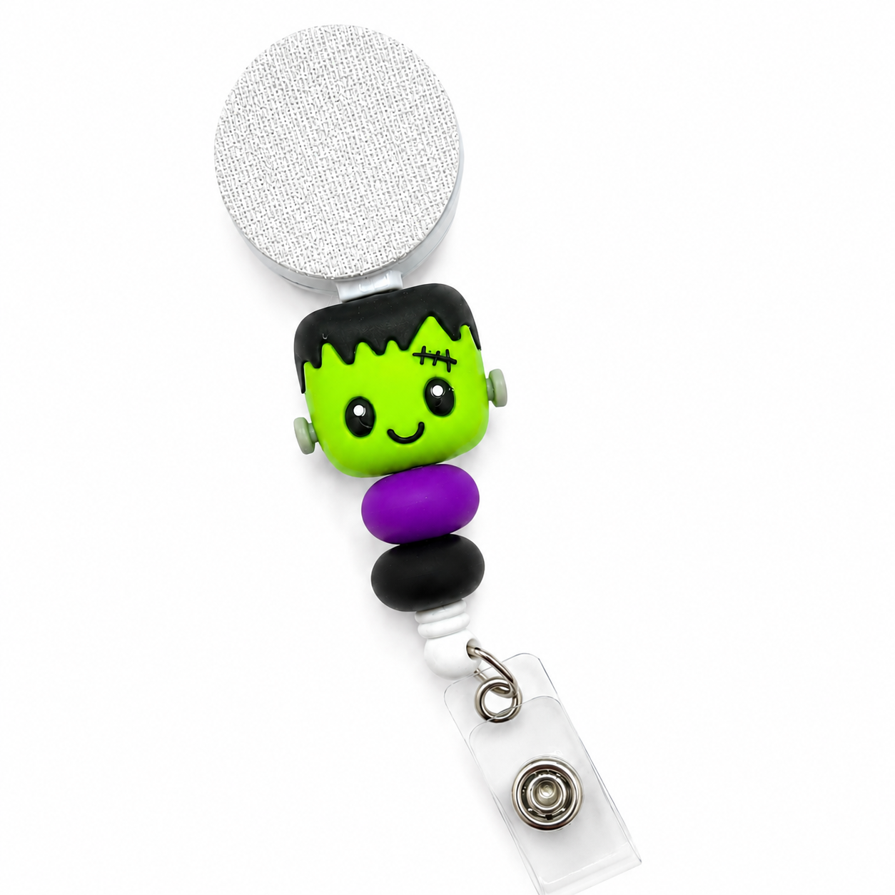 Frankenstein badge reel featuring a cute green Frankenstein monster with black hair, stitched details, purple and black decorative beads, retractable badge reel, and secure badge holder attachment.