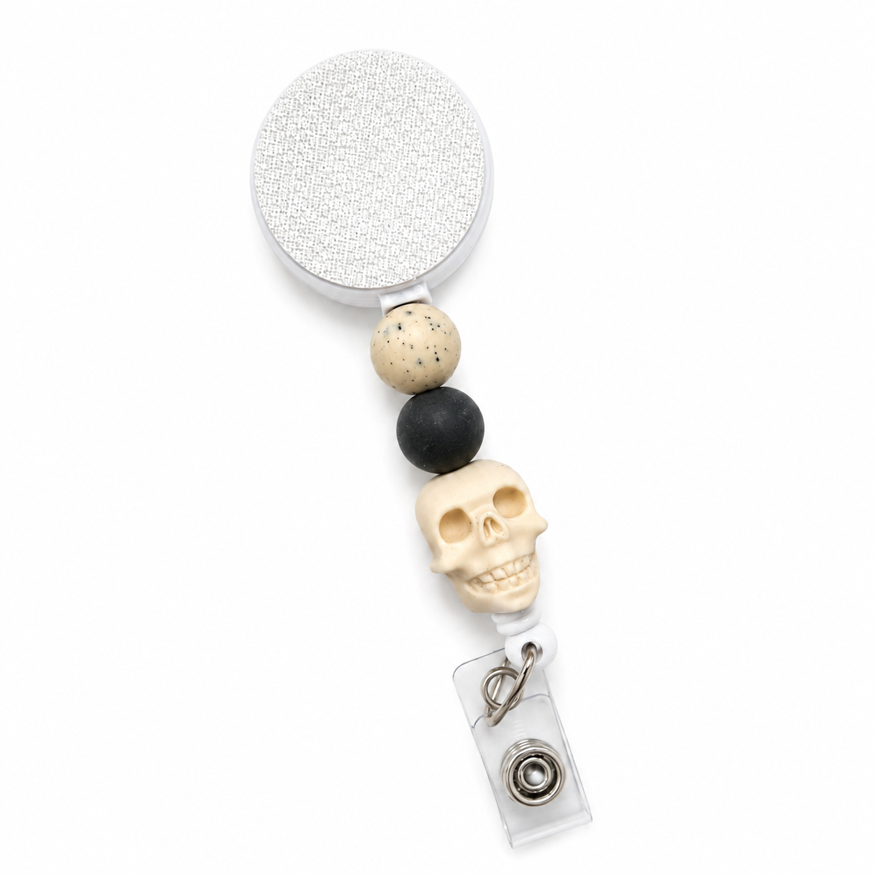 Ghostly Neutral badge reel featuring an ivory skull centerpiece with speckled cream and charcoal black decorative beads, retractable badge reel functionality, and a secure badge holder attachment.