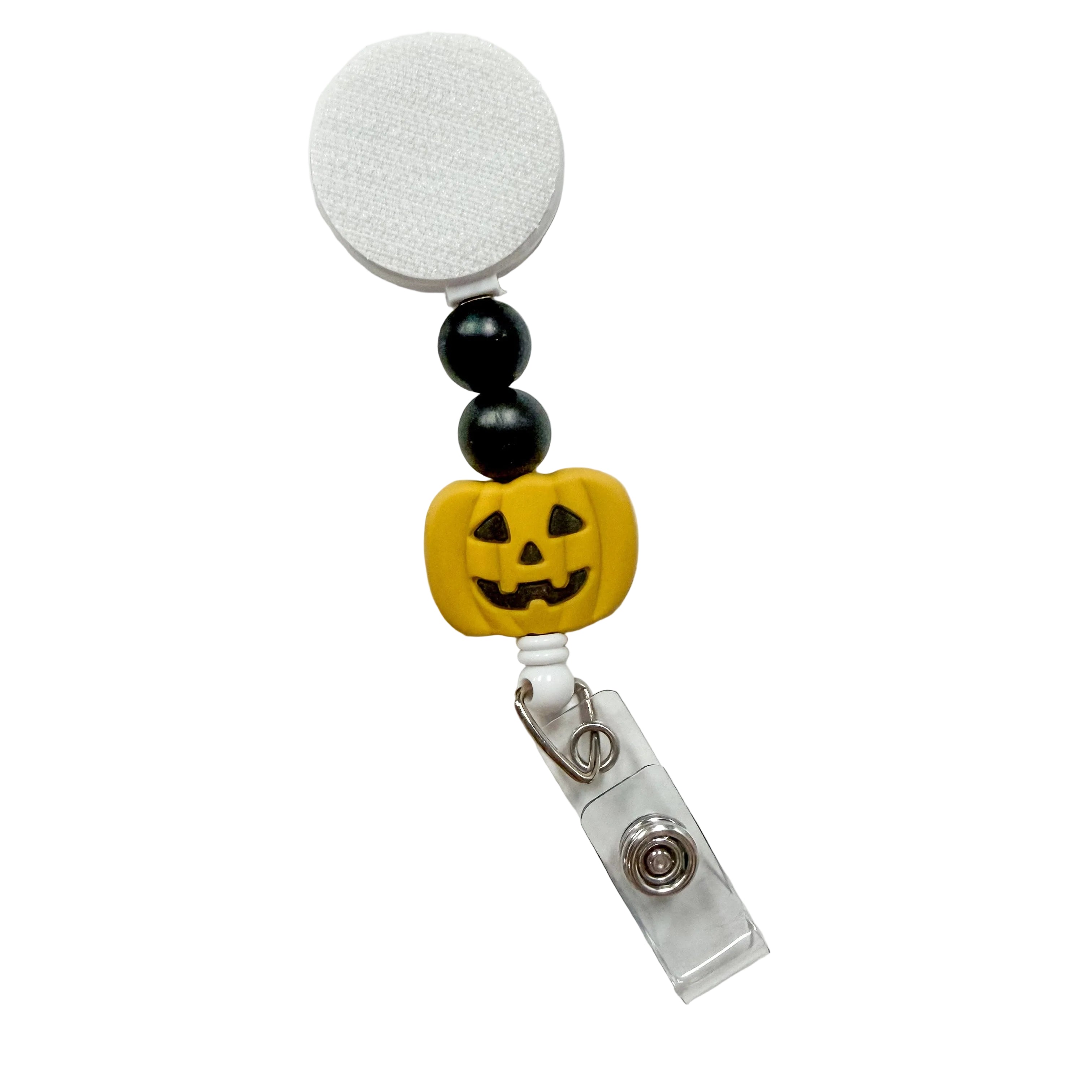 Golden Yellow Jack-o'-Lantern badge reel featuring a smiling carved pumpkin with black decorative beads, retractable badge reel functionality, and a secure badge holder attachment.