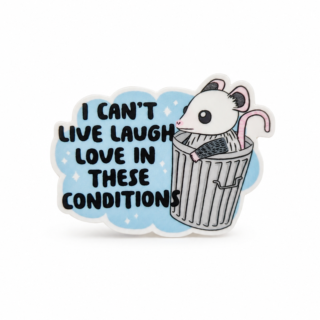 I CAN’T LIVE LAUGH LOVE IN THESE CONDITIONS plastic add-on with a white opossum in a gray trash can, compatible with interchangeable badge reel bases.