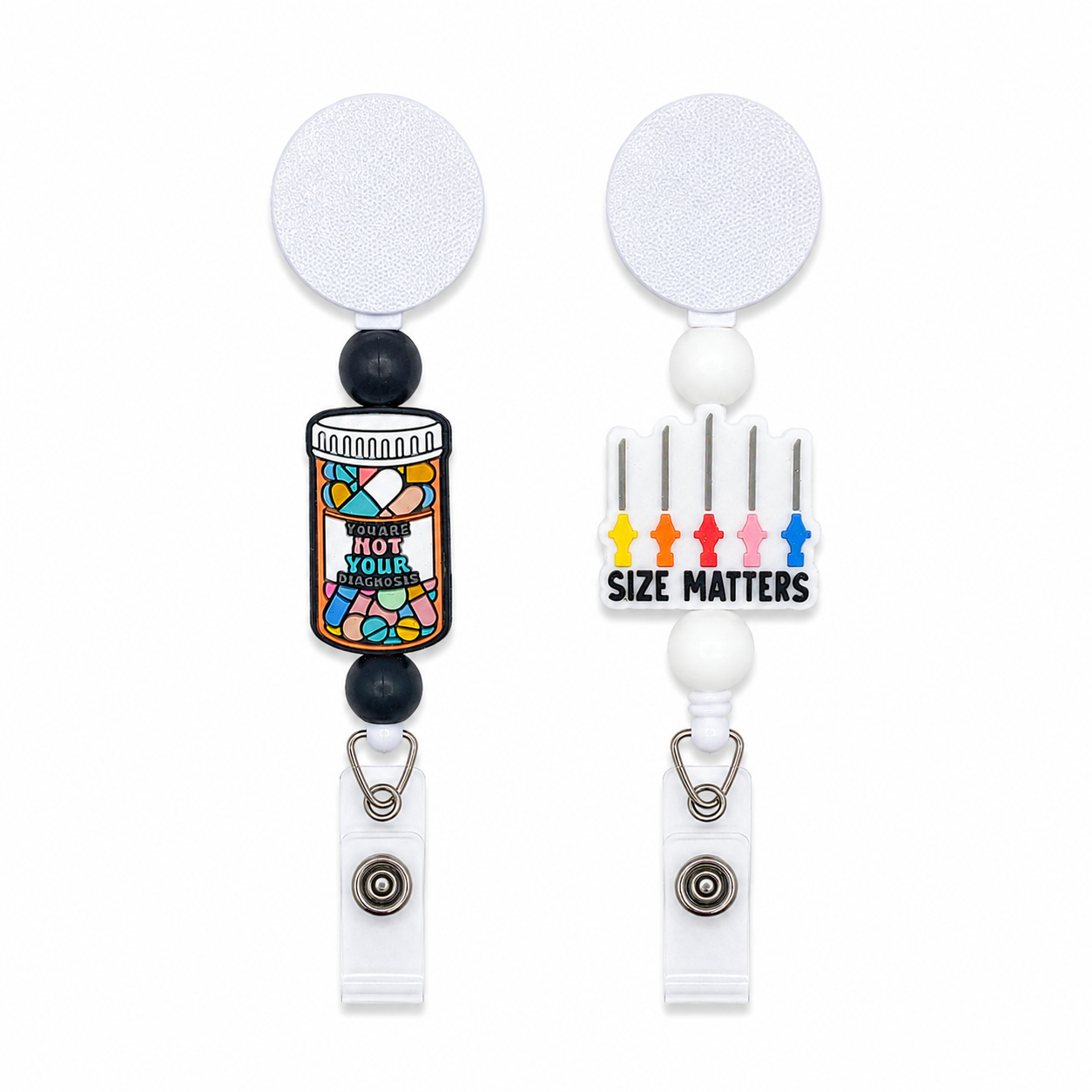 Medical humor badge reel available in a colorful You’re Not Your Diagnosis pill bottle design with navy beads or Size Matters syringes with white beads.