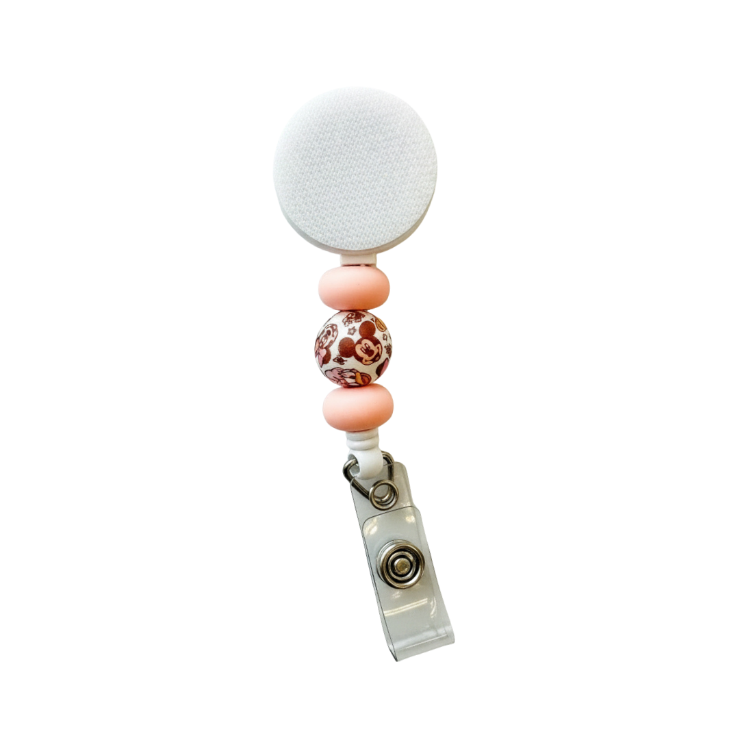 Interchangeable beaded badge reel featuring blush pink silicone beads and a mouse friends inspired printed focal bead on a white retractable badge reel.