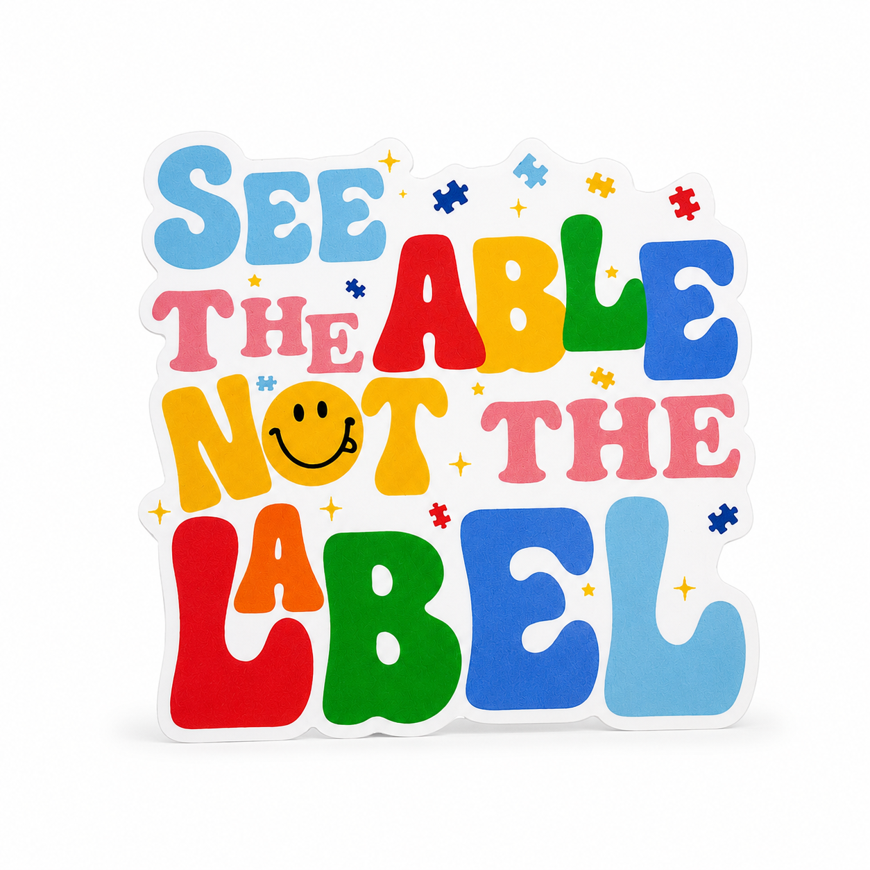 SEE THE ABLE NOT THE LABEL plastic add-on featuring colorful retro lettering, puzzle pieces, and smiley face, compatible with interchangeable badge reel bases and perfect for autism acceptance advocacy.