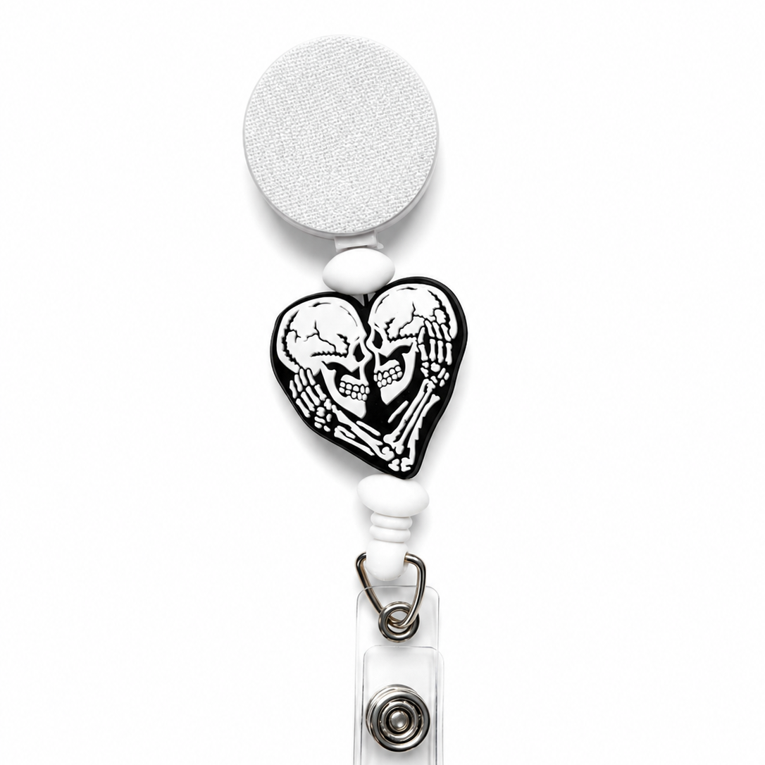 Spooky Sweetheart badge reel featuring a black heart-shaped skeleton design with white accent beads on a white retractable badge reel. Gothic Halloween work badge accessory.