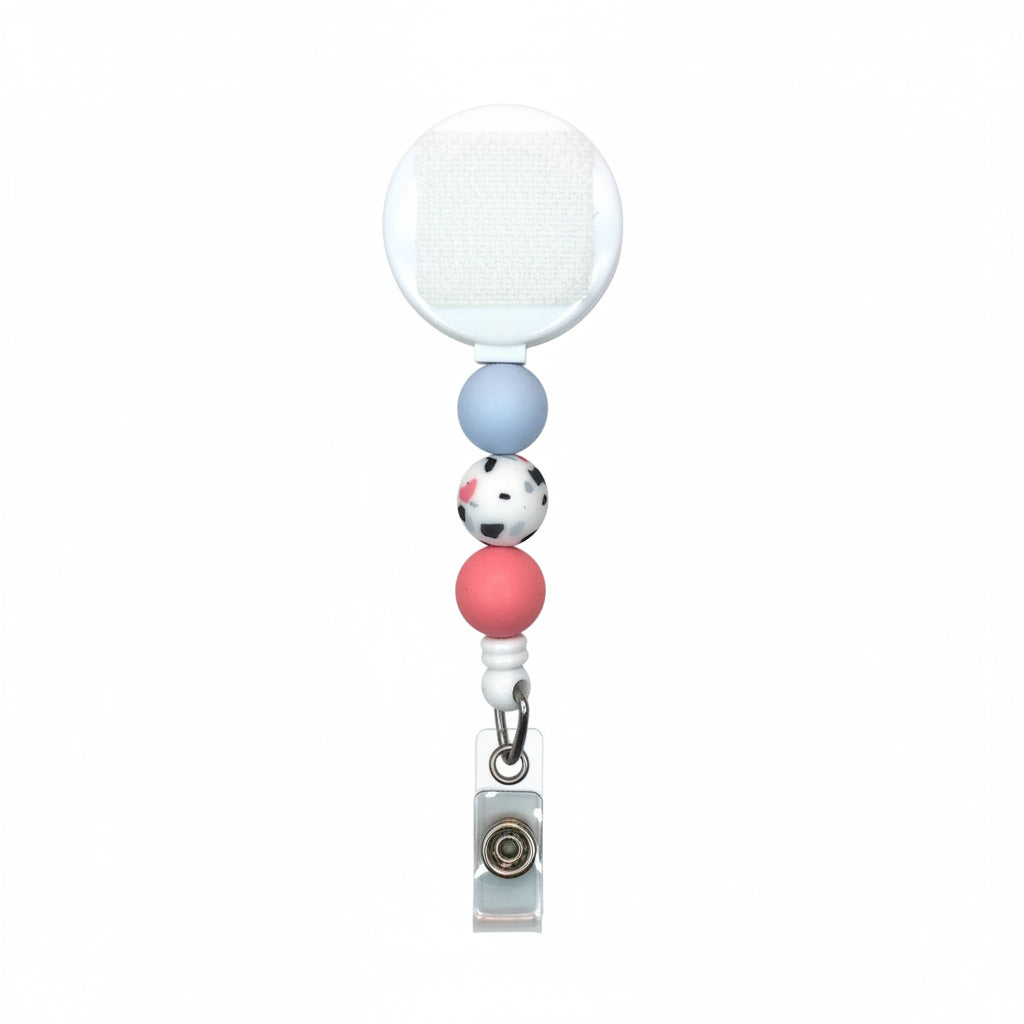 Interchangeable terrazzo badge reel with blue, speckled terrazzo, and coral silicone beads featuring a retractable badge holder for work.