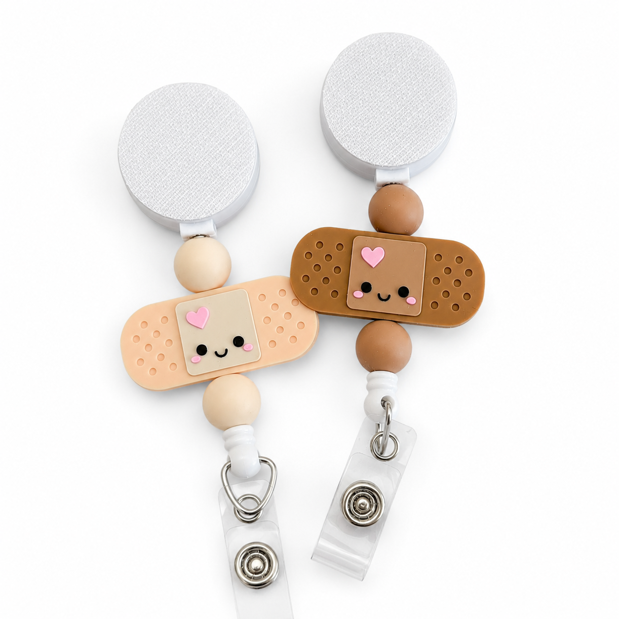 Cute bandage interchangeable badge reel featuring a smiling kawaii bandaid topper with cream or mocha colors, beads, and retractable badge holder.