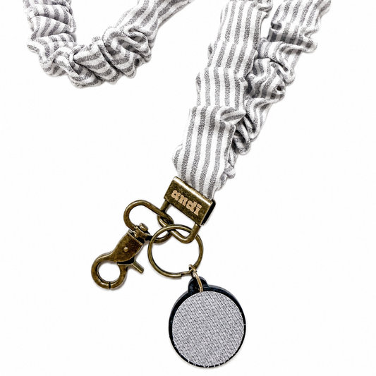 Gray Striped Interchangeable Andi Lanyard featuring a gray and white striped fabric design, interchangeable badge lanyard compatible with interchangeable hardboards and plastic add-ons.