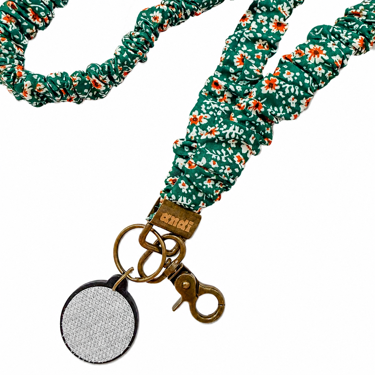 Green Floral Interchangeable Andi Lanyard featuring a teal green floral fabric design with white and orange flowers, compatible with interchangeable hardboards and plastic add-ons.