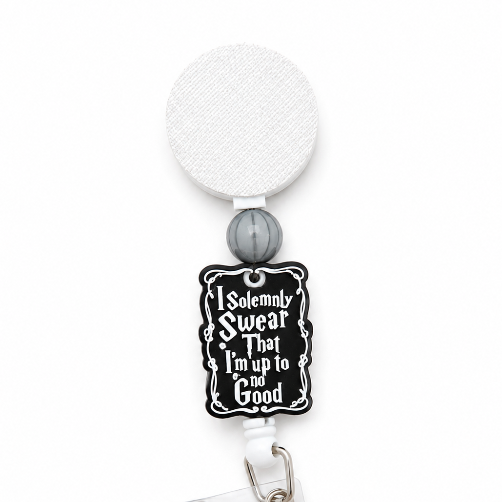 I Solemnly Swear That I'm Up to No Good badge reel with white retractable reel, gray silicone bead, and black decorative quote topper for work.