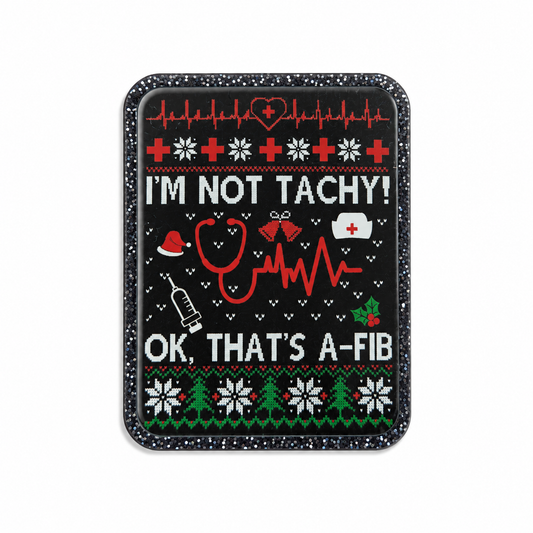 Plastic add-on featuring the phrase "I'M NOT TACHY! OK, THAT'S A-FIB" with EKG lines, stethoscope, syringe, nurse cap, and festive holiday details, compatible with interchangeable badge reel bases.