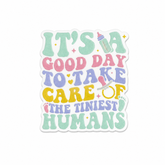 Plastic add-on featuring the phrase It's A Good Day To Take Care Of The Tiniest Humans with baby bottle, pacifier, and stethoscope design, compatible with interchangeable badge reel bases and ideal for pediatric and NICU nurses.