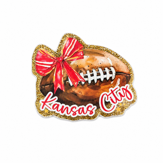 Kansas City plastic add-on featuring a football, red bow, and gold glitter accents, compatible with interchangeable badge reel bases and perfect for football fans.