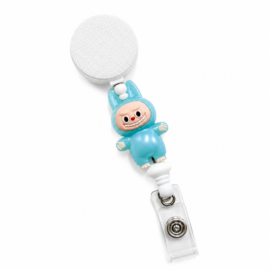 Little Blue Monster badge reel featuring a cute blue character design with white bead accents, retractable badge reel functionality, and a secure badge holder attachment.