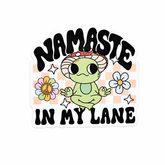 NAMASTE IN MY LANE plastic add-on with meditating green frog, mushroom hat, flowers, and checkered background, compatible with interchangeable badge reel bases.