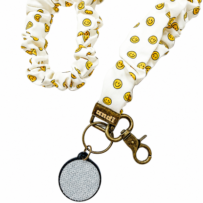 No Worries Interchangeable Andi Lanyard featuring a white fabric design with yellow smiley face pattern, compatible with interchangeable hardboards and plastic add-ons.