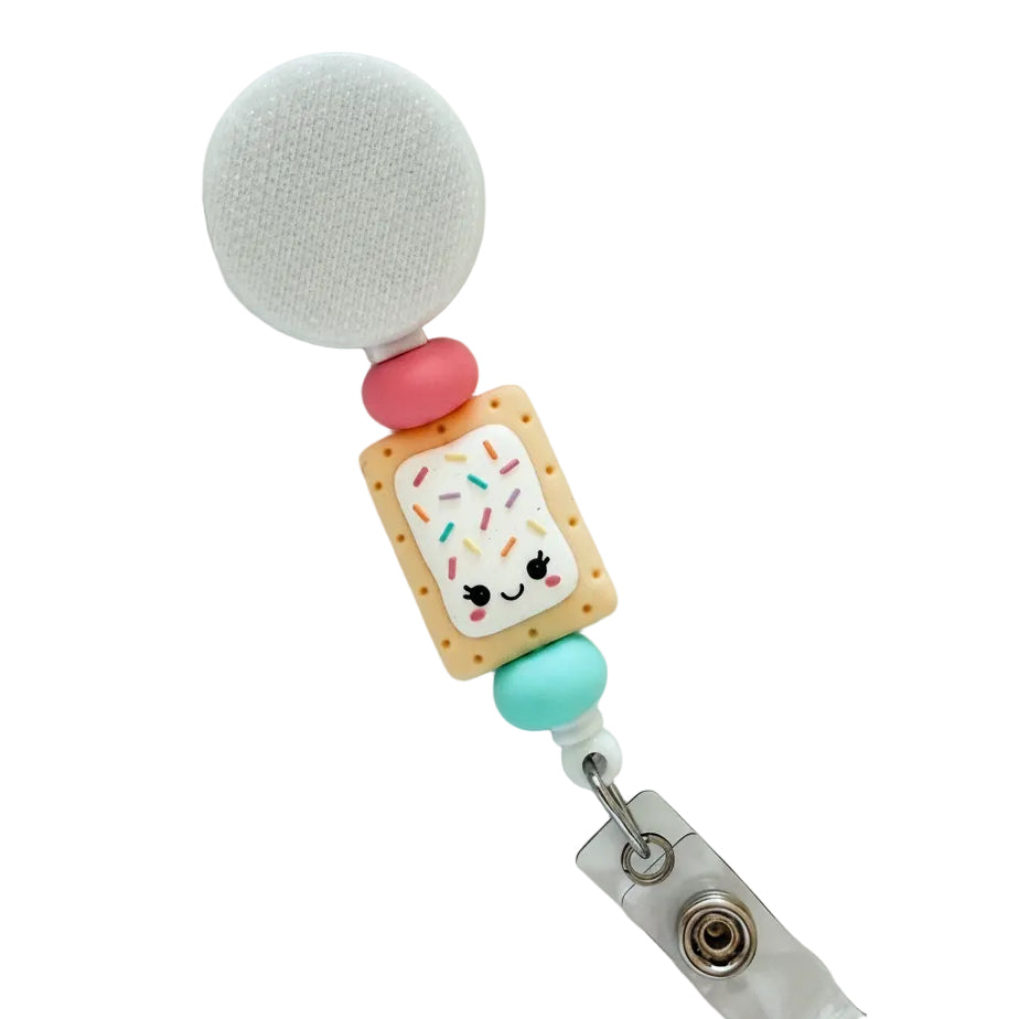 Cute Pop Tart badge reel featuring a smiling frosted pastry with colorful sprinkles, pink and aqua silicone beads, and a white retractable badge reel for nurses, teachers, and healthcare professionals.
