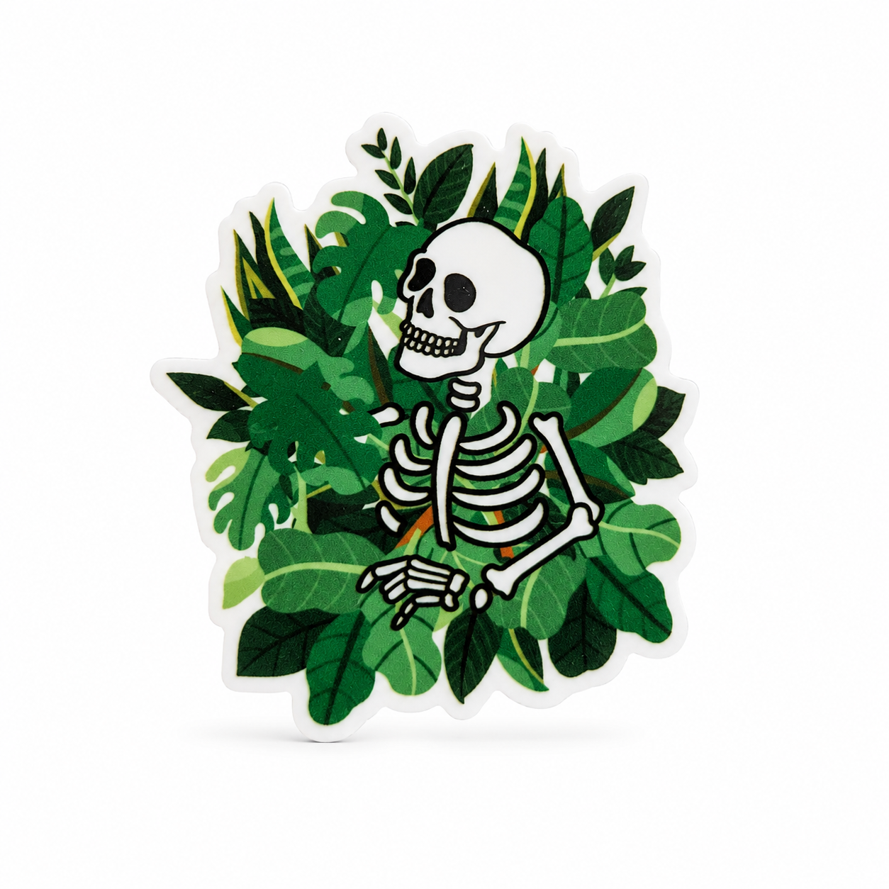 Plastic add-on with a smiling skeleton surrounded by lush green leaves, compatible with interchangeable badge reel bases.