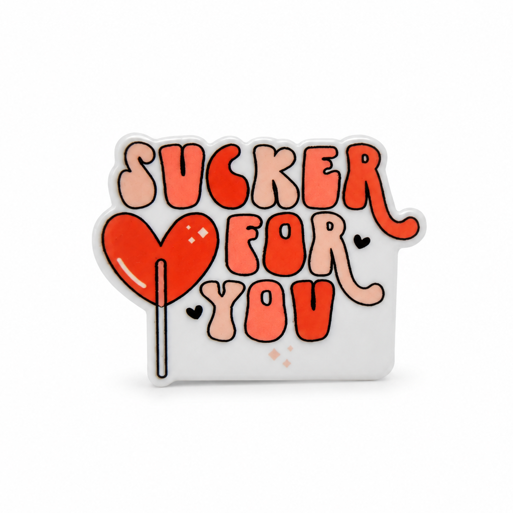 Sucker For You plastic add-on featuring a heart-shaped lollipop and playful lettering, compatible with interchangeable badge reel bases for Valentine's Day.