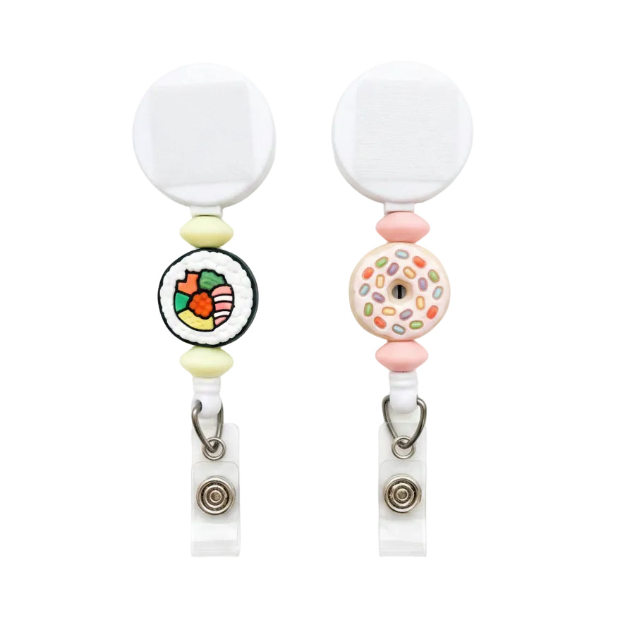 Sushi and donut badge reel variants featuring a colorful sushi roll with pale yellow beads or a sprinkle donut with pink beads on white retractable reels.