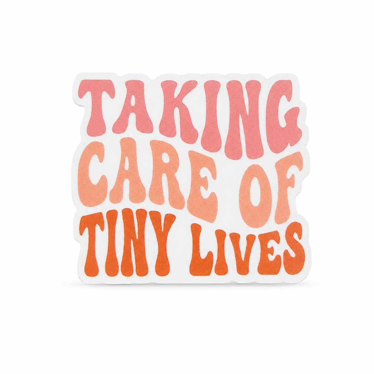 TAKING CARE OF TINY LIVES plastic add-on with pink, peach, and orange lettering, compatible with interchangeable badge reel bases for NICU and pediatric nurses.