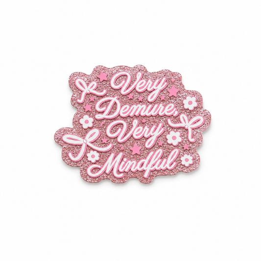 Very Demure Very Mindful plastic add-on featuring a pink glitter-inspired background, bows, and flowers, compatible with interchangeable badge reel bases and perfect for trendy feminine aesthetics.