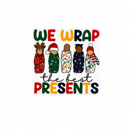 Plastic add-on featuring swaddled Christmas babies and the phrase WE WRAP the best PRESENTS, compatible with interchangeable badge reel bases, perfect for Labor and Delivery and NICU nurses.